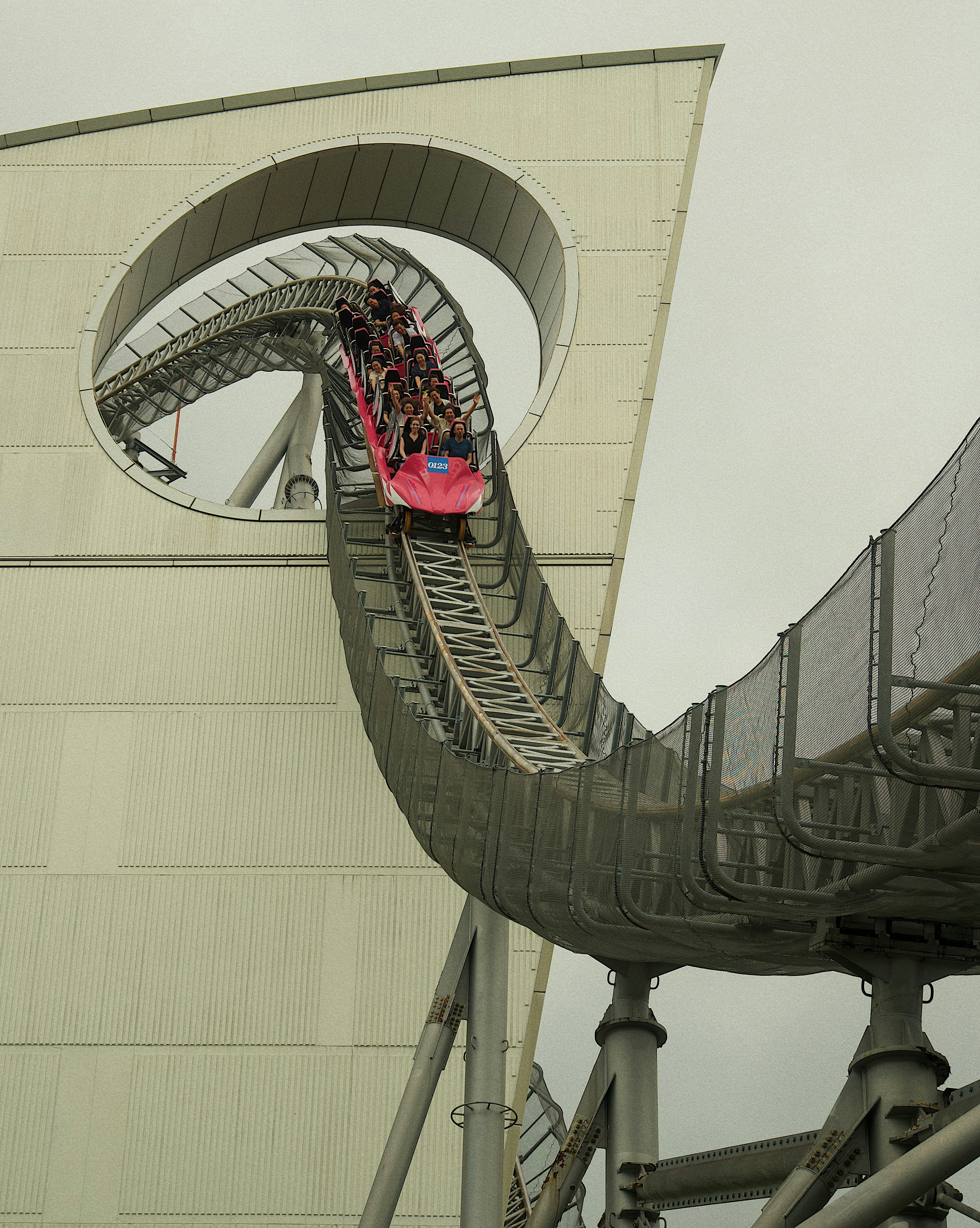 The famous Tokyo Dome City roller coaster going through the round cut-out in the wall.